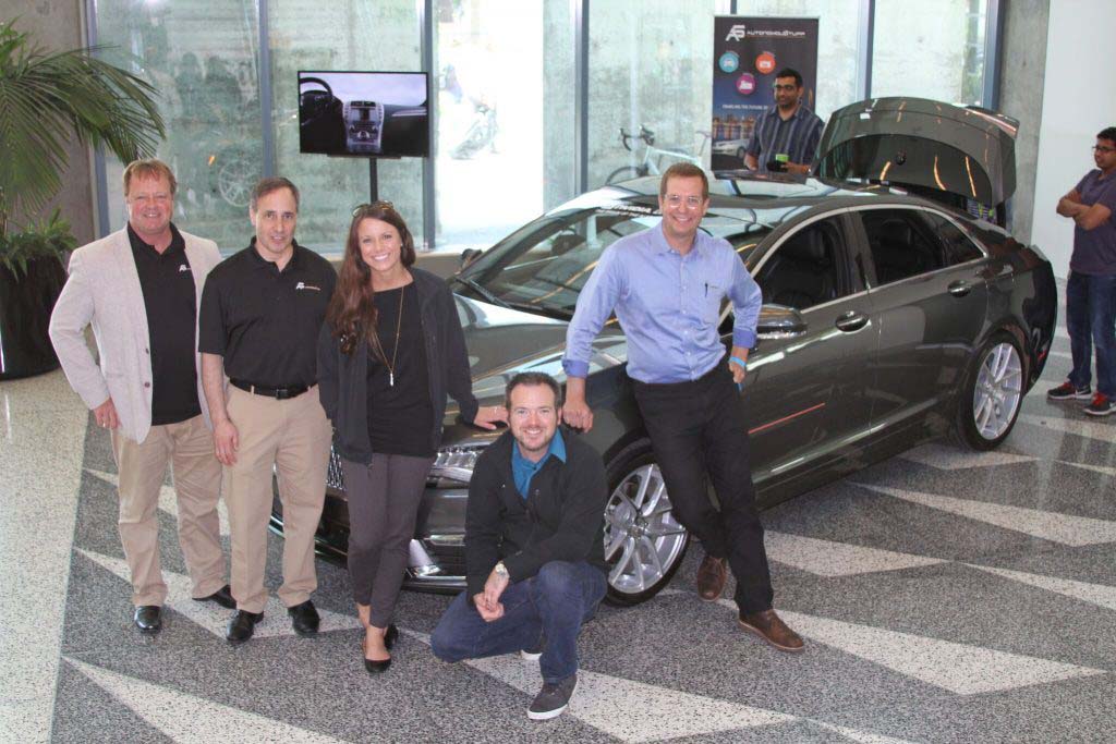 Five people standing in front of a car